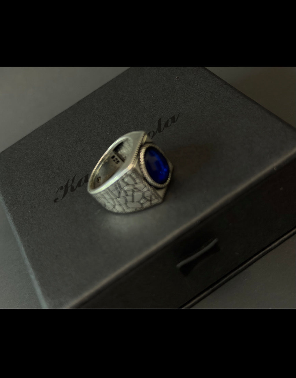 Men's 925 sterling silver ring with a blue synthetic stone and engraved textured band.